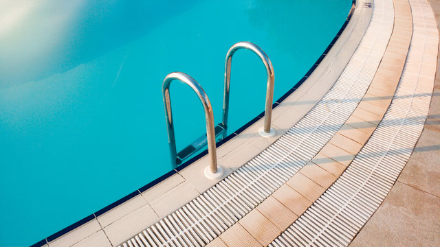 Closeup image of metal starcase on the poolside at early sunny morning