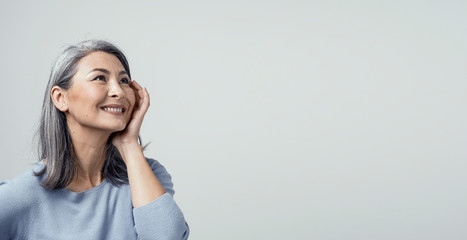 Side profile of charming asian woman smiling on white background