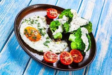 Fried egg with vegetables on wooden table