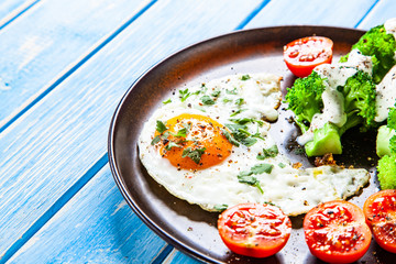 Fried egg with vegetables on wooden table