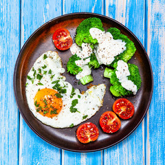 Fried egg with vegetables on wooden table