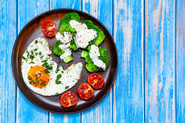 Fried egg with vegetables on wooden table
