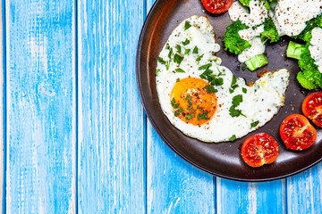 Fried egg with vegetables on wooden table