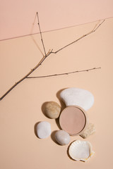 Stones on pastel background with an opened powder. Abstract still life. Makeup collection 8.