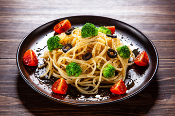 Pasta with herbs and vegetables on wooden background
