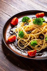 Pasta with herbs and vegetables on wooden background