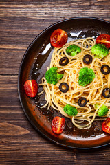Pasta with herbs and vegetables on wooden background