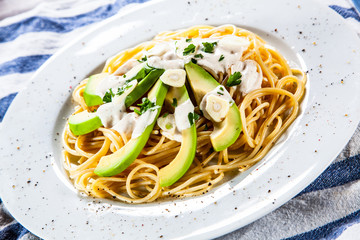 Pasta with avocado on wooden table