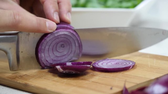 Cutting red onion on a wooden board
