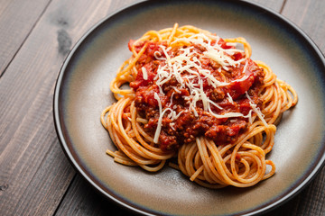 Spaghetti Bolognese sauce or tomato sauce on a dark wooden board, traditional Italian food closeup and top view
