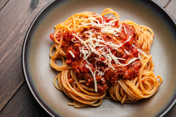 Spaghetti Bolognese sauce or tomato sauce on a dark wooden board, traditional Italian food closeup and top view