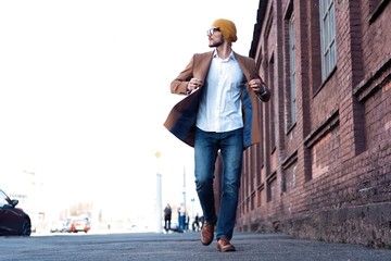 Cool man beautiful model outdoors, city style fashion. A handsome man model walking in the city center. Urban setting