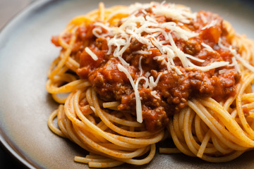 Spaghetti Bolognese sauce or tomato sauce on a dark wooden board, traditional Italian food closeup and top view