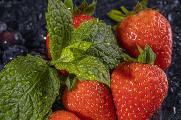 fresh red strawberries macro on black table waterdrops leaf