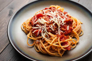 Spaghetti Bolognese sauce or tomato sauce on a dark wooden board, traditional Italian food closeup and top view