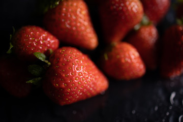 fresh red strawberries macro on black table waterdrops