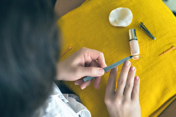 Top  view on woman sitting on the armchair and doing manicure at home.