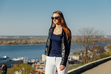 Portrait of a stylish dark-haired girl in sunglasses, she is in a leather jacket