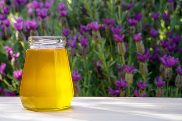 Honey in glass jar on wooden table on nature lavender background. Outdoor