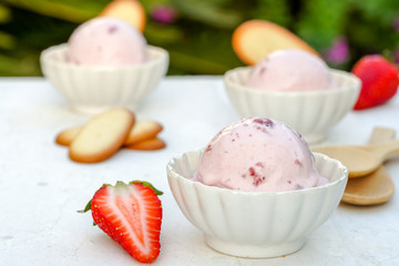 Tasty  strawberry ice cream  in bowls on table against nature flowers background	