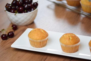 Vanilla muffins with cherry on a white plate.