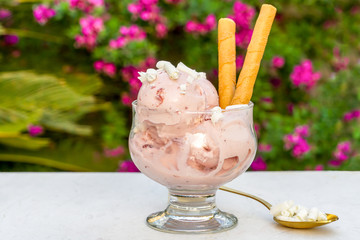 Tasty  strawberry ice cream  in bowl on table against nature flowers background	