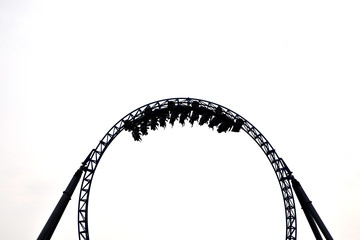 Silhouette of people having fun on a roller-coaster in an amusement park at sunset. Adrenalin...