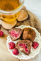 Homemade healthy vegan chocolate truffles with raspberry, dates, coconut flakes and rolled oats served on wooden plate.Close-up.