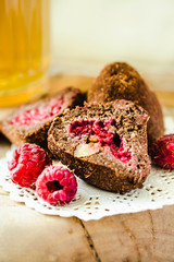 Chocolate candy truffle with raspberry on a wooden stand with glass of green tea. Close-up.