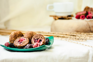Homemade chocolate truffle with fresh raspberry in the green plate on white linen tablecloth backgound.