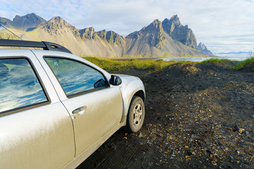 Fototapeta na wymiar Dirty silver color car on countryside road in Vesturhorn Mountain in summer morning. Stokksnes, Iceland, Northern Europe, Scandinavia. Scenic beautiful nature landscape. Popular tourist attraction.