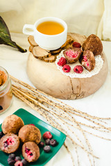 Served chocolate balls pralines with fresh berries in the green plate on white linen tablecloth backgound. A cup of herbal tea and glass of Cocoa powder.