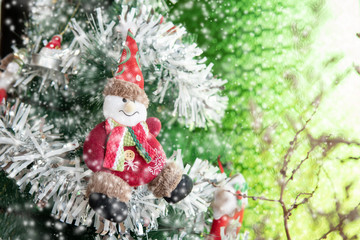 Merry Christmas and happy new year concept, Close Up of Doll hanging from a decorated tree with bokeh and snow, Xmas holiday background.