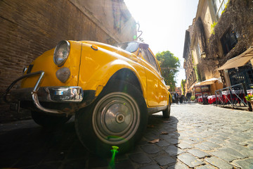 Fototapeta premium An old retro yellow car standing on Italian street