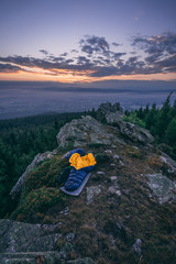 An opened sleeping bag laying on the ground on a rock, forest in the background. Sunrise or sunset...