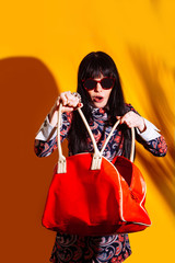shopper woman yellow background red shadow bag brunette glasses funny shopping