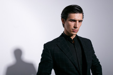 Portrait of attractive man in black suit, isolated on white background. Horizontal indoors shot.