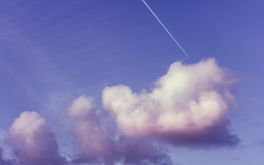 Naklejka na ściany i meble Airplane piercing dreamy fluffy clouds on blue sky