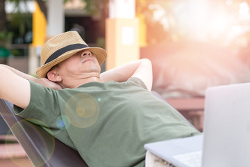 Easy relax business man lifestyle with computer in hotel resort sitting hands behind head for happy businessman people with work life balance. Simplify Your Life Week. International happiness day.