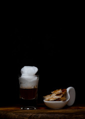 Coffee with foam in a small tube glass on a wood.