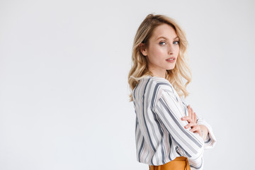 Half turn portrait of blond smiling woman wearing casual clothes looking at camera with arms crossed