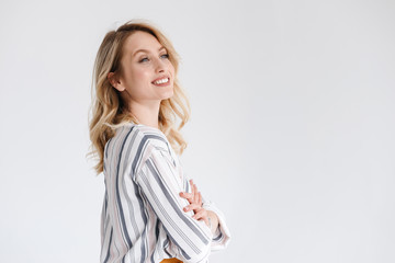 Half turn portrait of young smiling woman wearing casual clothes looking aside at copyspace with arms crossed