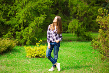 Fototapeta premium Young girl walks along in white jacket and jeans by park