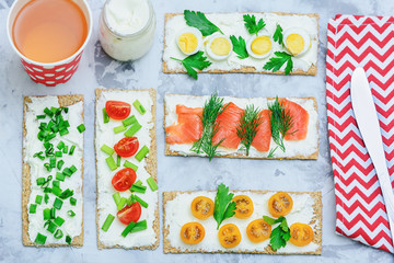 Crispbread smeared with curd cheese. Sandwiches with trout tomatoes, parsley and onions. Delicious, wholesome breakfast. Photo above, flat lay.