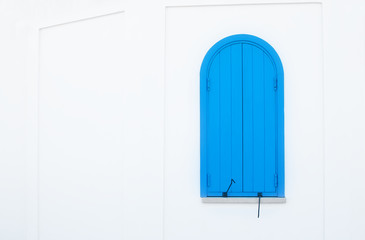 One small arched blue door with metal hinges on a plain white wall