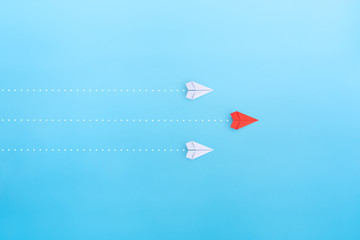Leadership concept with red paper plane leading among white on blue background, copy space