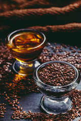 flax seeds and linseed oil in glass sauceboats on a black stone