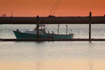 Sunset with a fishing boat moored to a dock