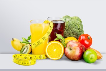 Glasses of fresh juice and fruits with vegetables and measuring tape