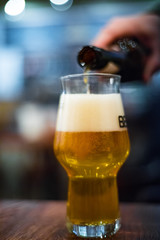 pouring beer from bottle into glass at bar